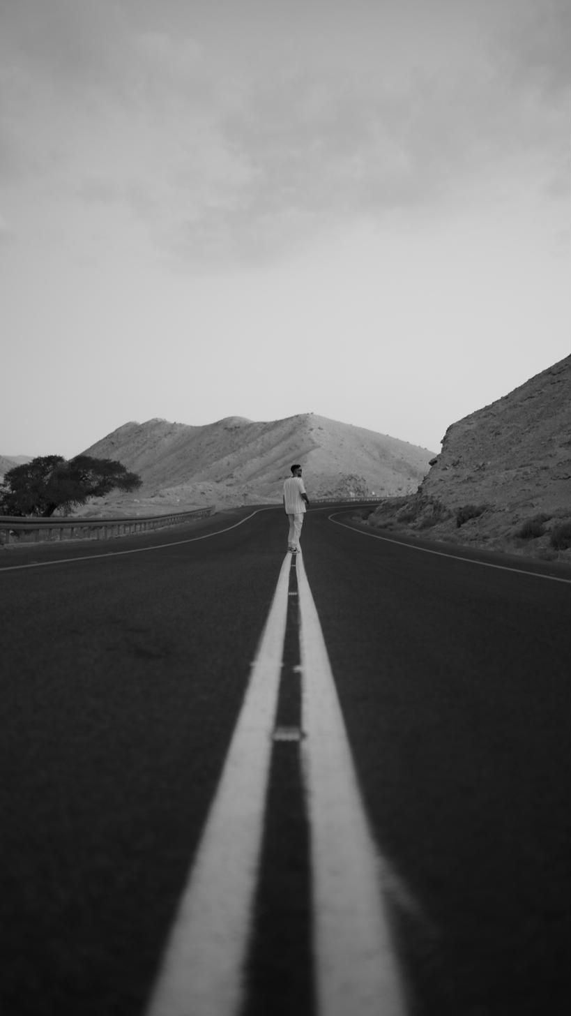 A single figure walking the centre line of an empty desert road
